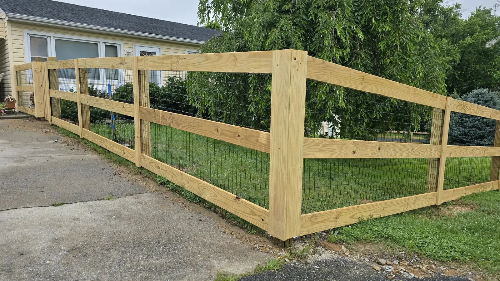 Pressure-treated post-and-wire fence with wide gate built in Maryland